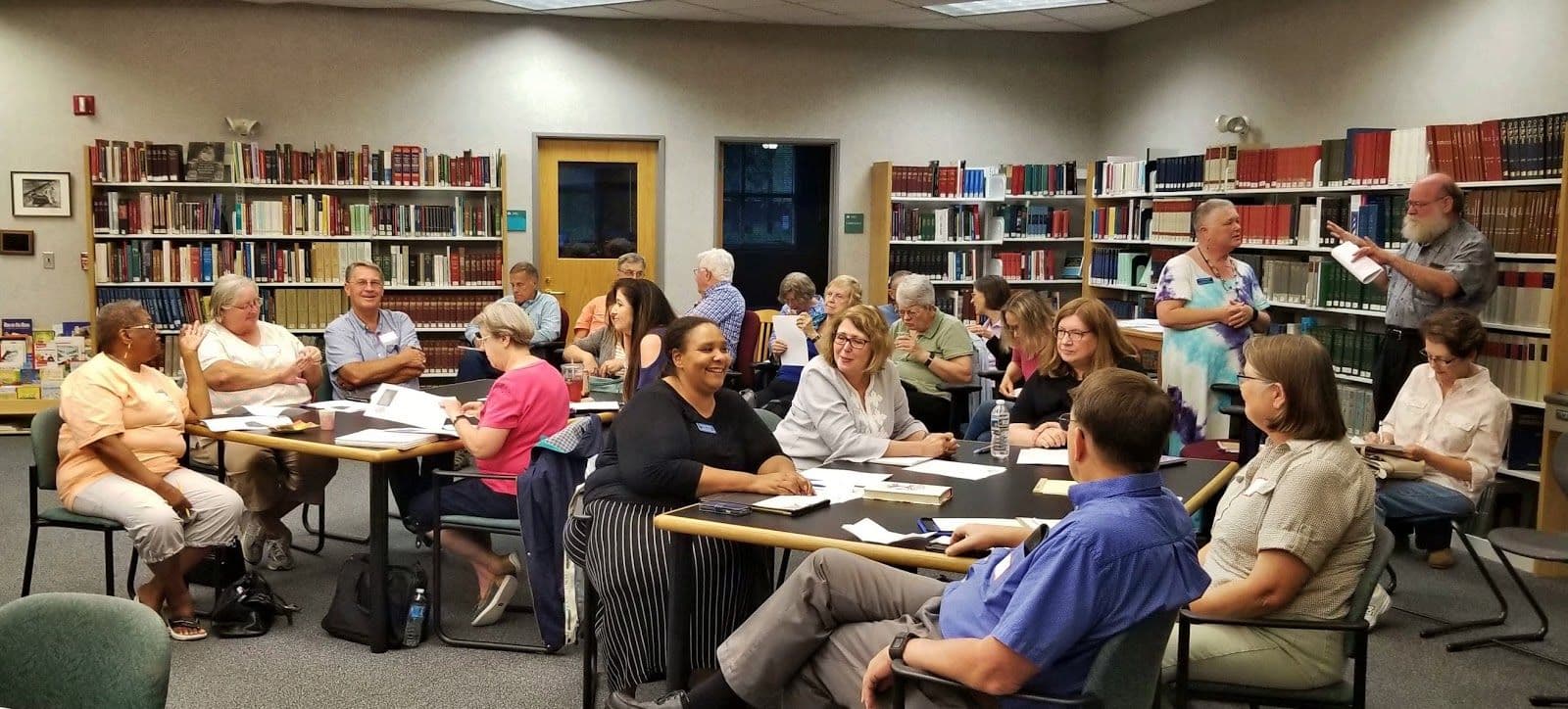 Wake County Genealogical Society participants talking around tables lined with research books