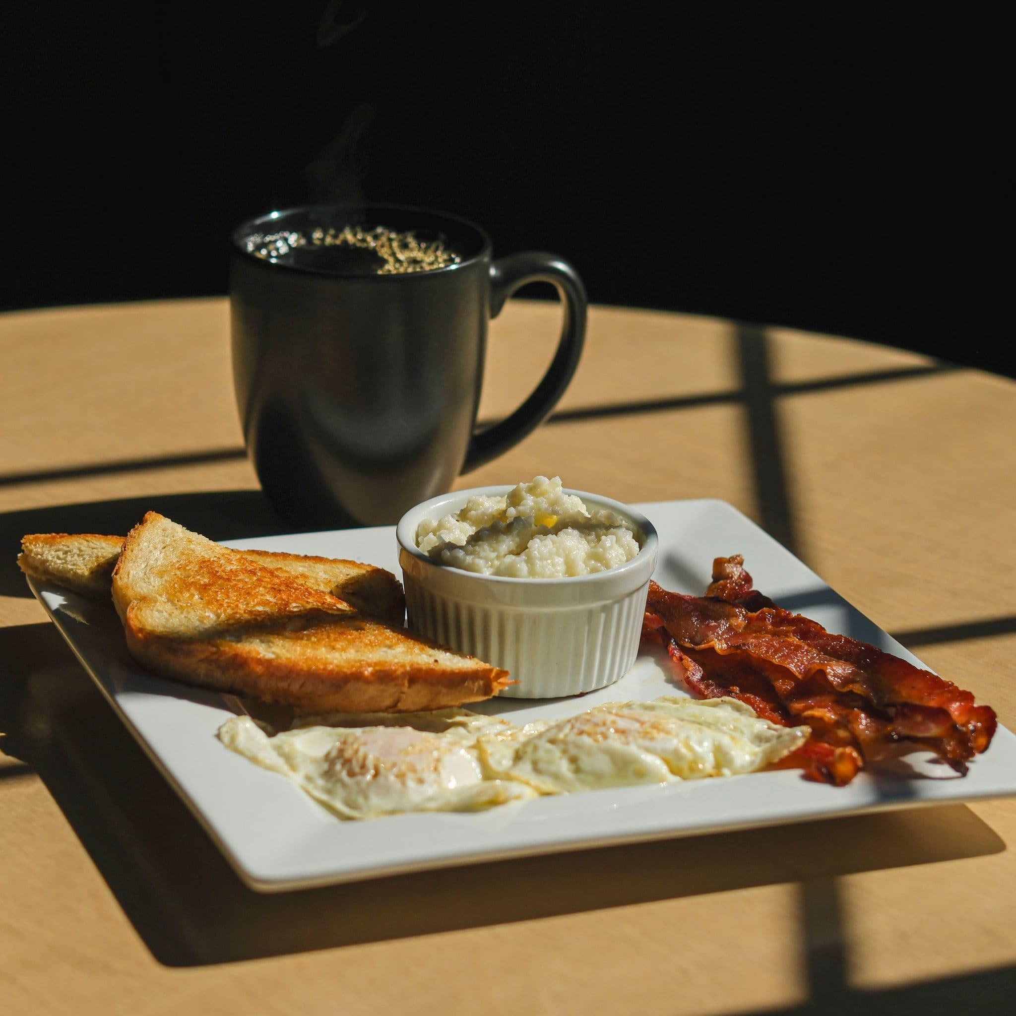 Breakfast and a black coffee mug on a sunlit table at 41 North Coffee