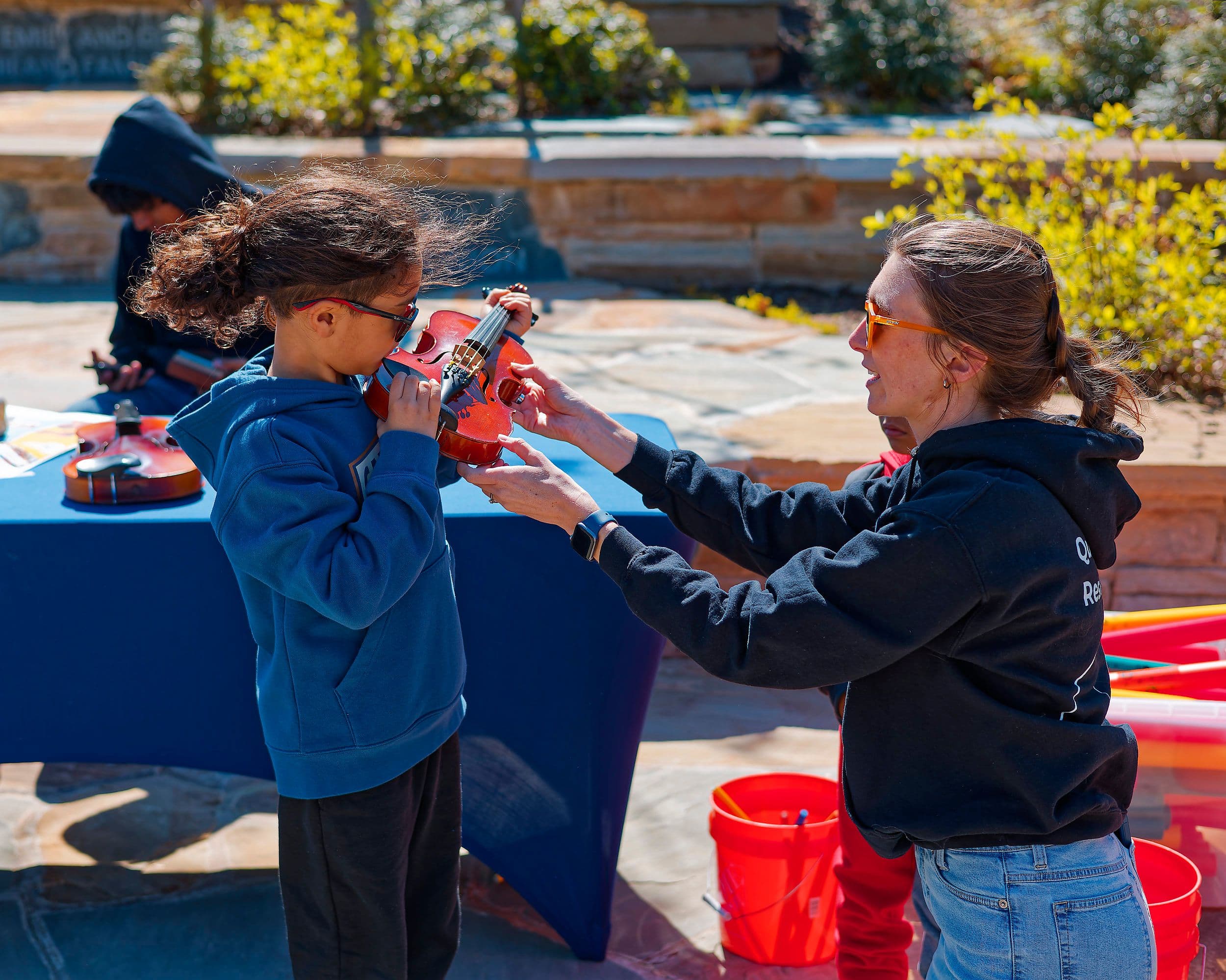A child tries a violin with help from an adult during Dix Park’s instrument program