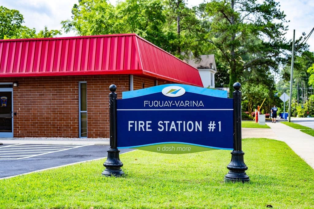 A blue Fire Station No. 1 sign in front of the brick Fuquay-Varina fire station