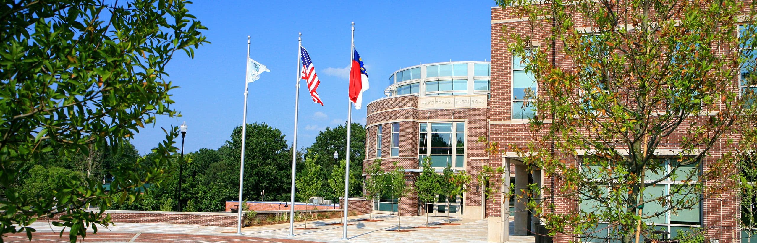 Wake Forest Town Hall’s brick facade and three flags outside the entrance