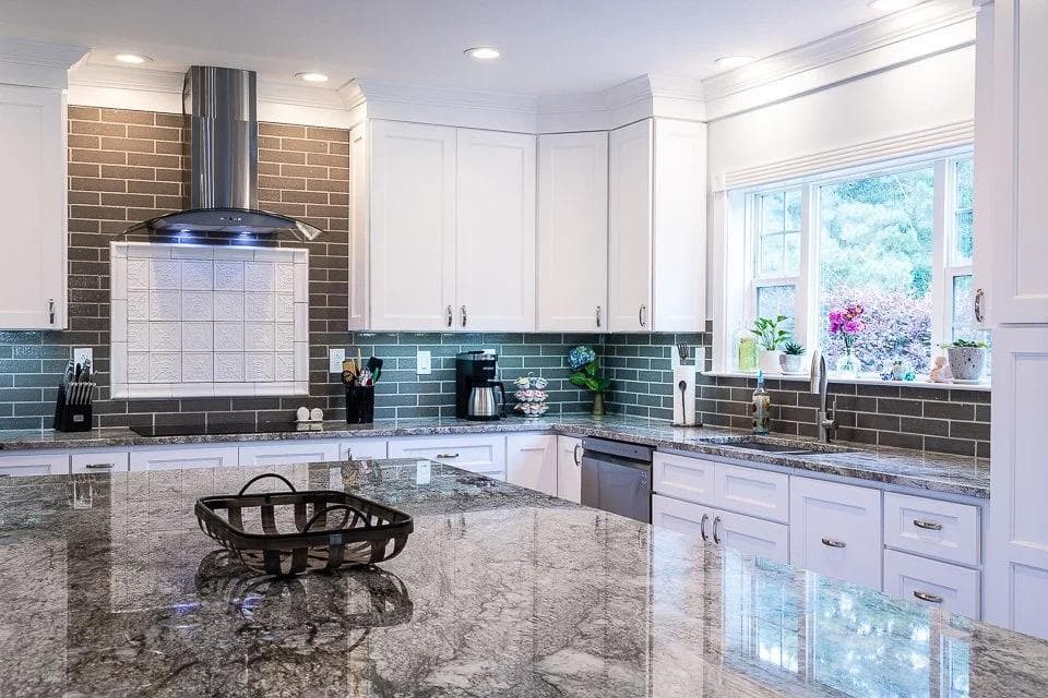 White kitchen with a dark subway tile backsplash and a wide stone countertop