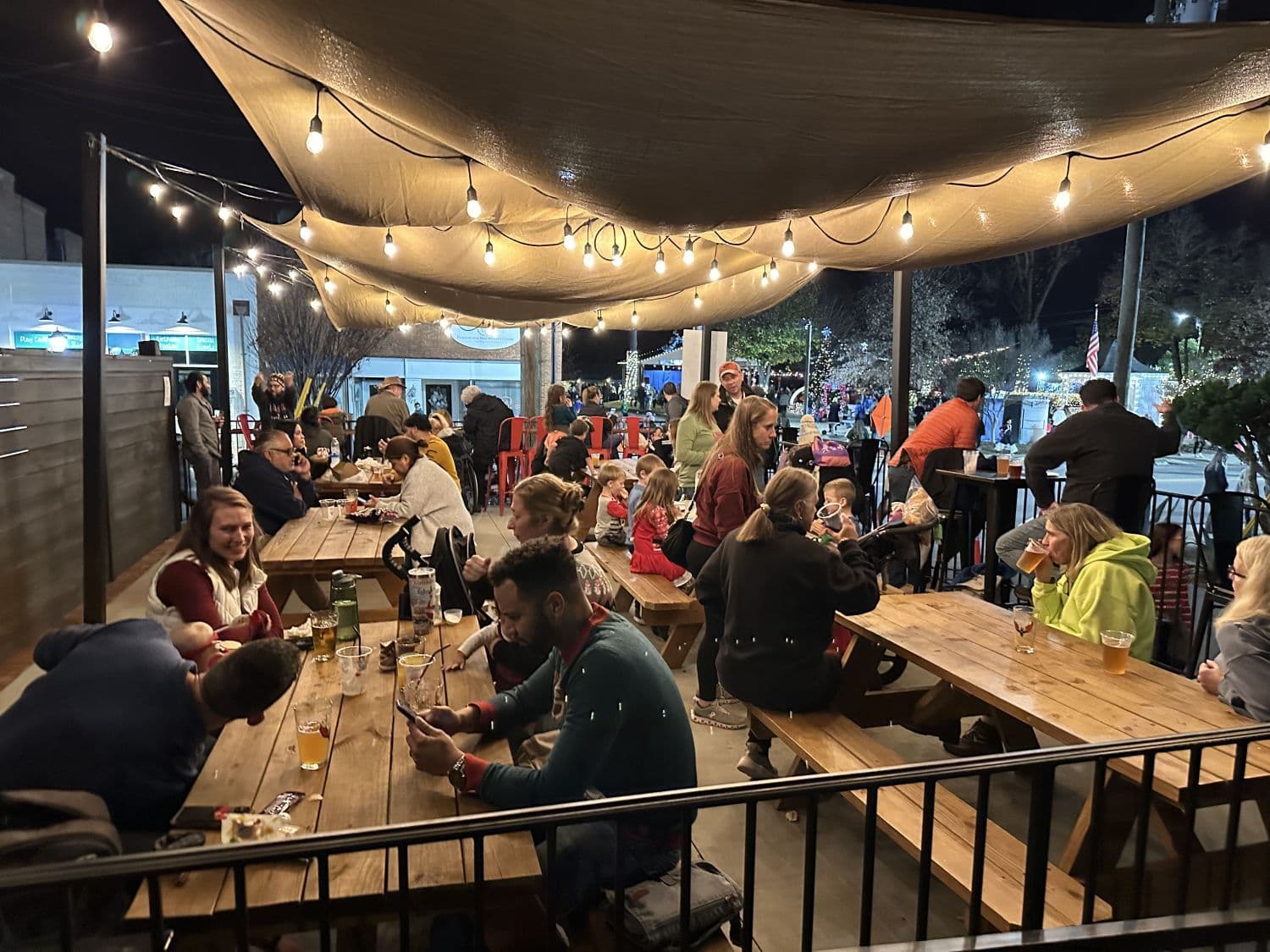 Guests sitting together under string lights on Carolina Brewing’s Wendell patio