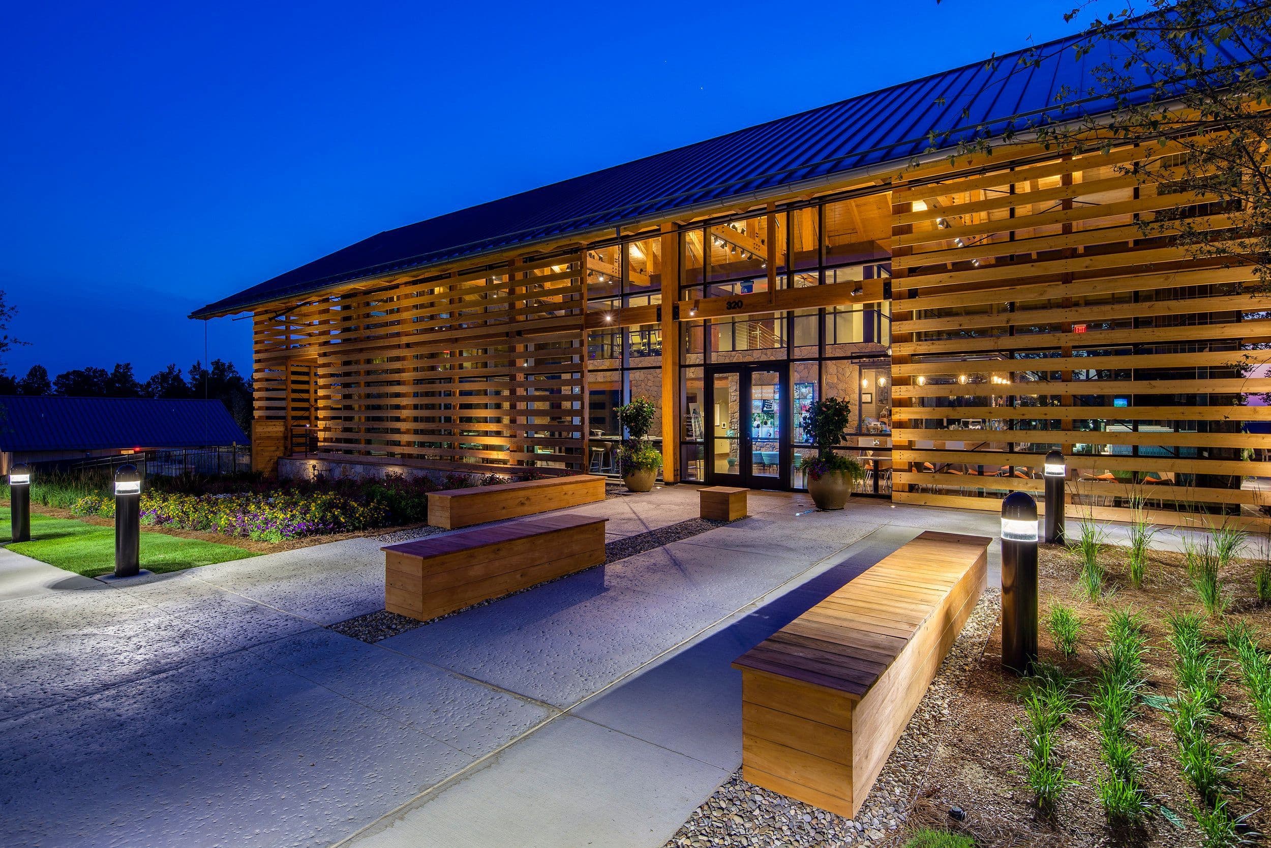 Farmhouse Cafe’s wood and glass building illuminated at dusk