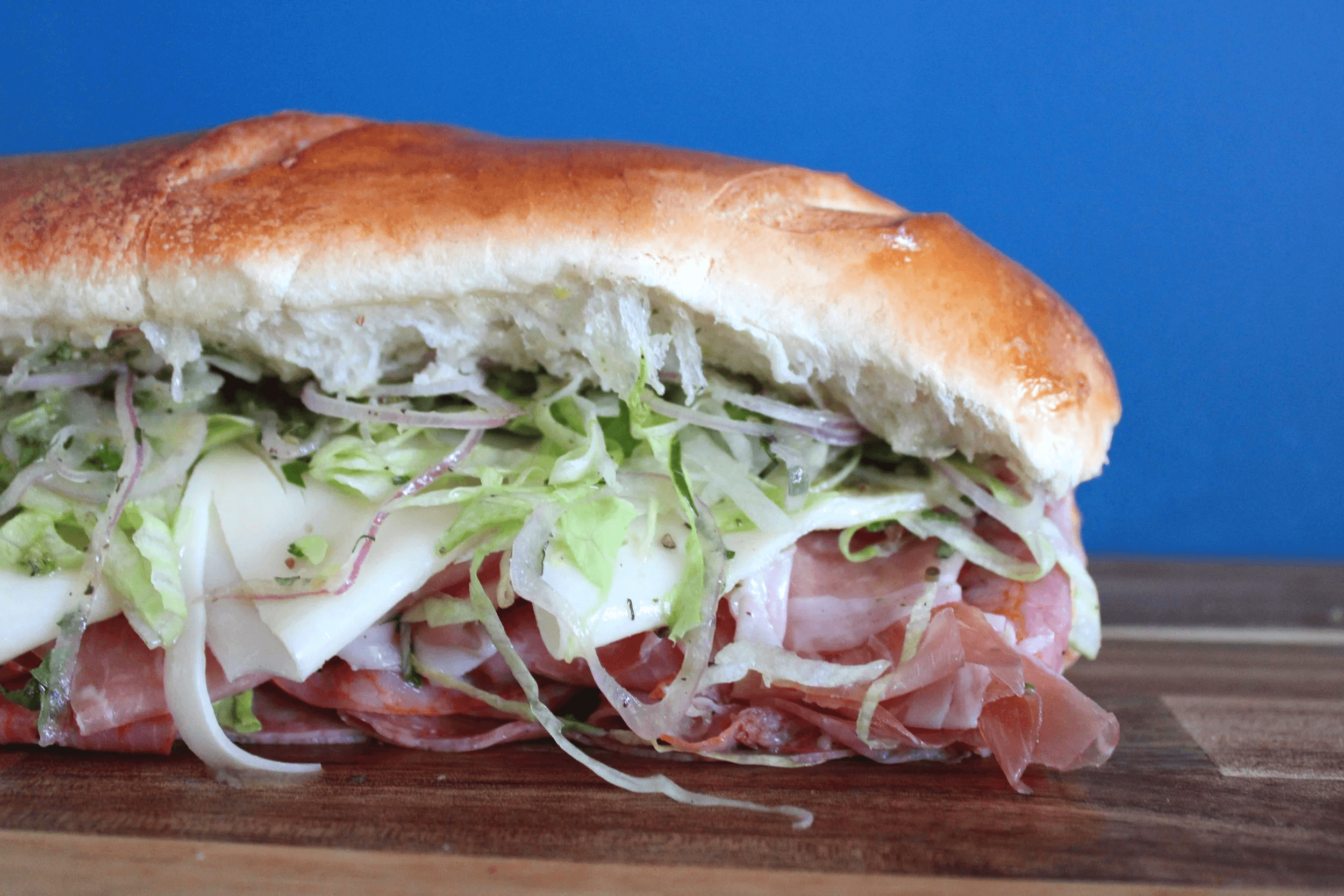 Deli sandwich stacked with meat, cheese and shredded lettuce from Bellow Butcher Co.